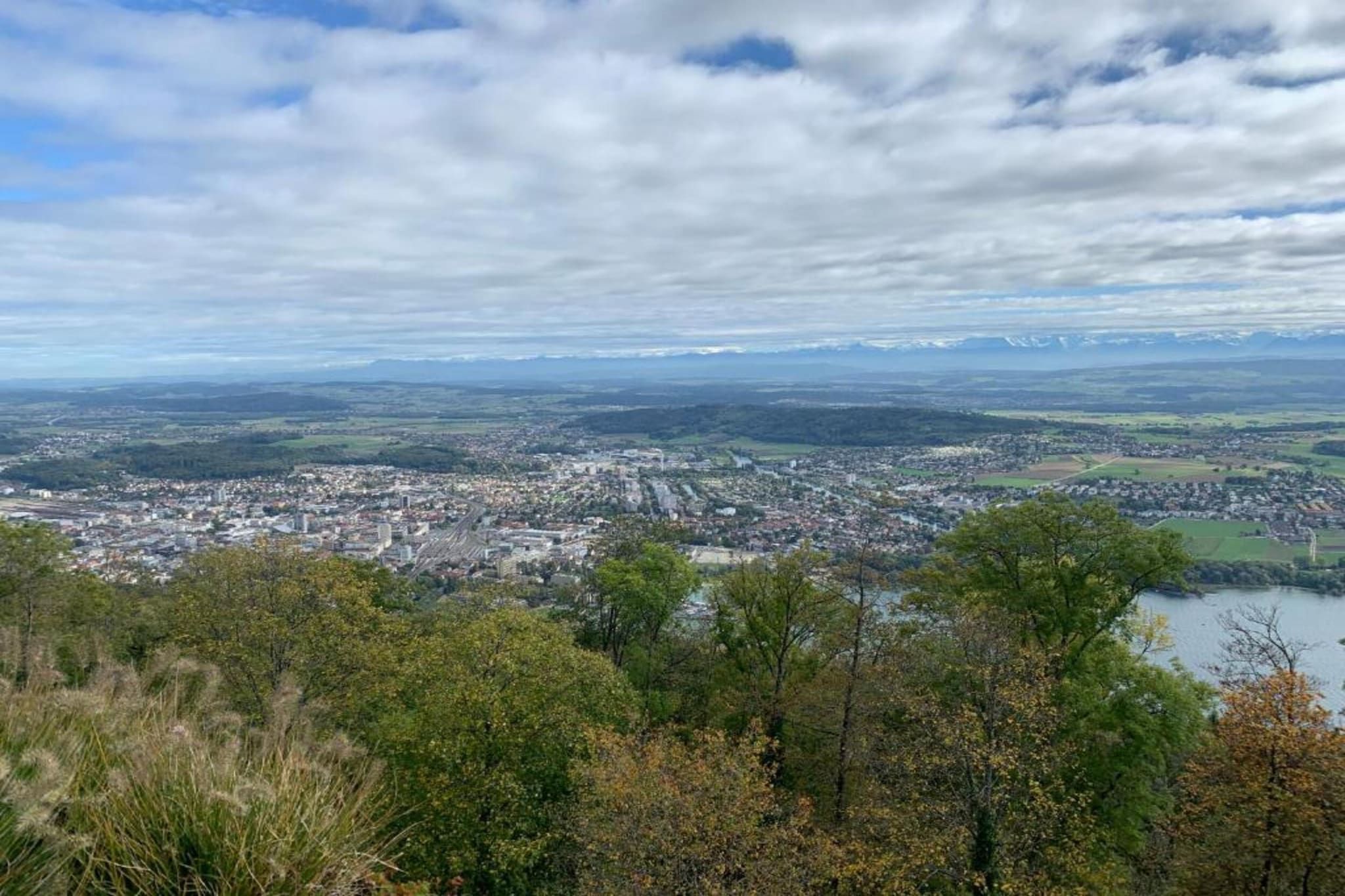 A panoramic view of a city with a river, surrounded by hills and mountains.