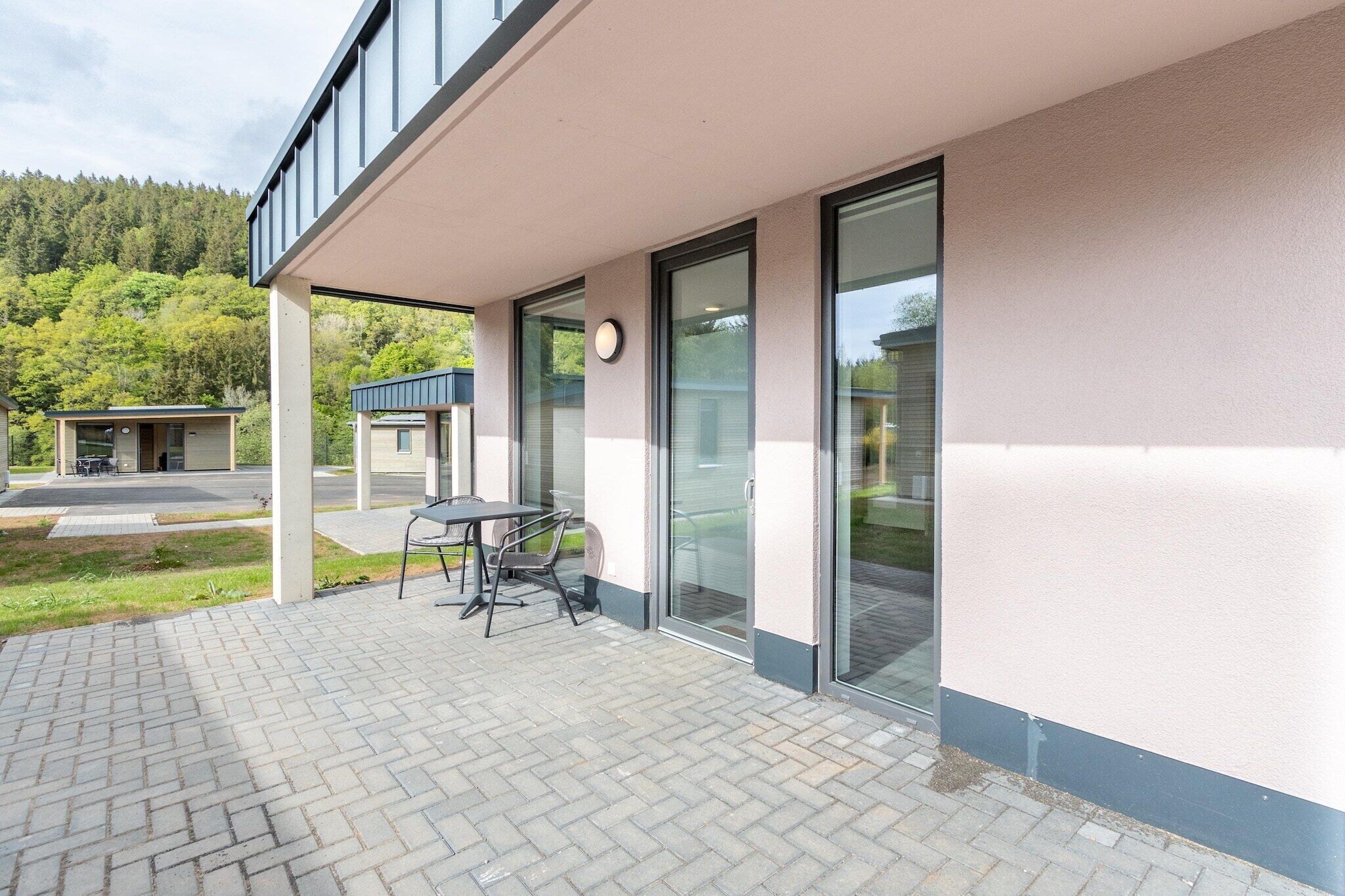 Ein modernes Gebäude mit überdachter Terrasse, ausgestattet mit Tisch und Stühlen.