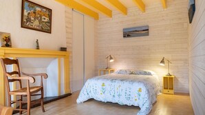 A bedroom with a bed, two bedside lamps, a wooden chair, a small table, and a painting on the wall. - Stone-house cottage in Saussey with garden (Saussey)