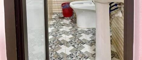 Un baño pequeño con ducha, inodoro y lavamanos.