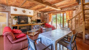 Un salon chaleureux avec une cheminée, des murs en pierre et un plafond en bois.