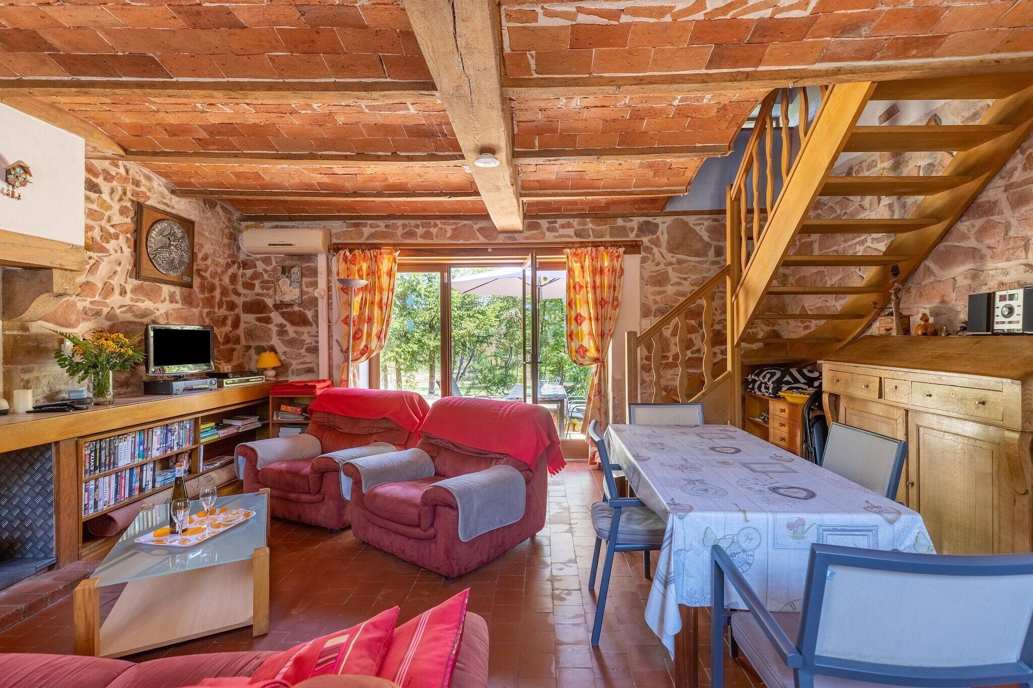 Un salon chaleureux avec une cheminée, un coin repas et un escalier menant à l’étage supérieur.