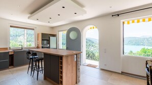Una cocina moderna con una isla de madera, taburetes de bar y grandes ventanales con vistas panorámicas.