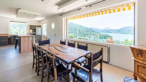 Una cocina moderna con una isla grande, un área de comedor con una mesa y sillas de madera, y un ventanal con vistas a la montaña.