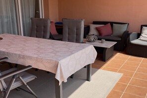 A dining area with a table covered in a patterned tablecloth, surrounded by chairs and a sofa with cushions. - Belvilla by OYO Mar Menor (Torre-Pacheco)