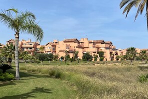 A residential area with multiple buildings, palm trees, and a grassy field. - Belvilla by OYO Mar Menor (Torre-Pacheco)