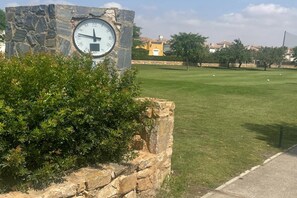 A stone clock mounted on a wall with a grassy area in the foreground. - Belvilla by OYO Mar Menor (Torre-Pacheco)
