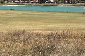 A golf course with a water body in the background and a building complex across the water. - Belvilla by OYO Mar Menor (Torre-Pacheco)