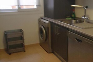 A kitchen with a washing machine, a dishwasher, and a metal rack. - Belvilla by OYO Mar Menor (Torre-Pacheco)