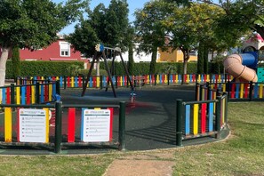 A playground with a swing set, a slide, and a climbing structure. - Belvilla by OYO Mar Menor (Torre-Pacheco)