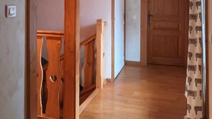 Un escalier en bois mène à une pièce dotée d’une porte en bois et d’un rideau à motifs.