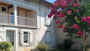 Un bâtiment à deux étages doté d’un balcon, d’une cour verdoyante et d’une chaise.