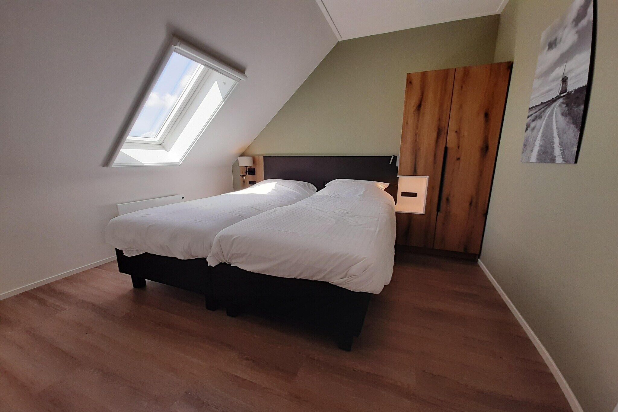 Une chambre avec un puits de lumière, un lit, une armoire en bois et une lampe fixée au mur.