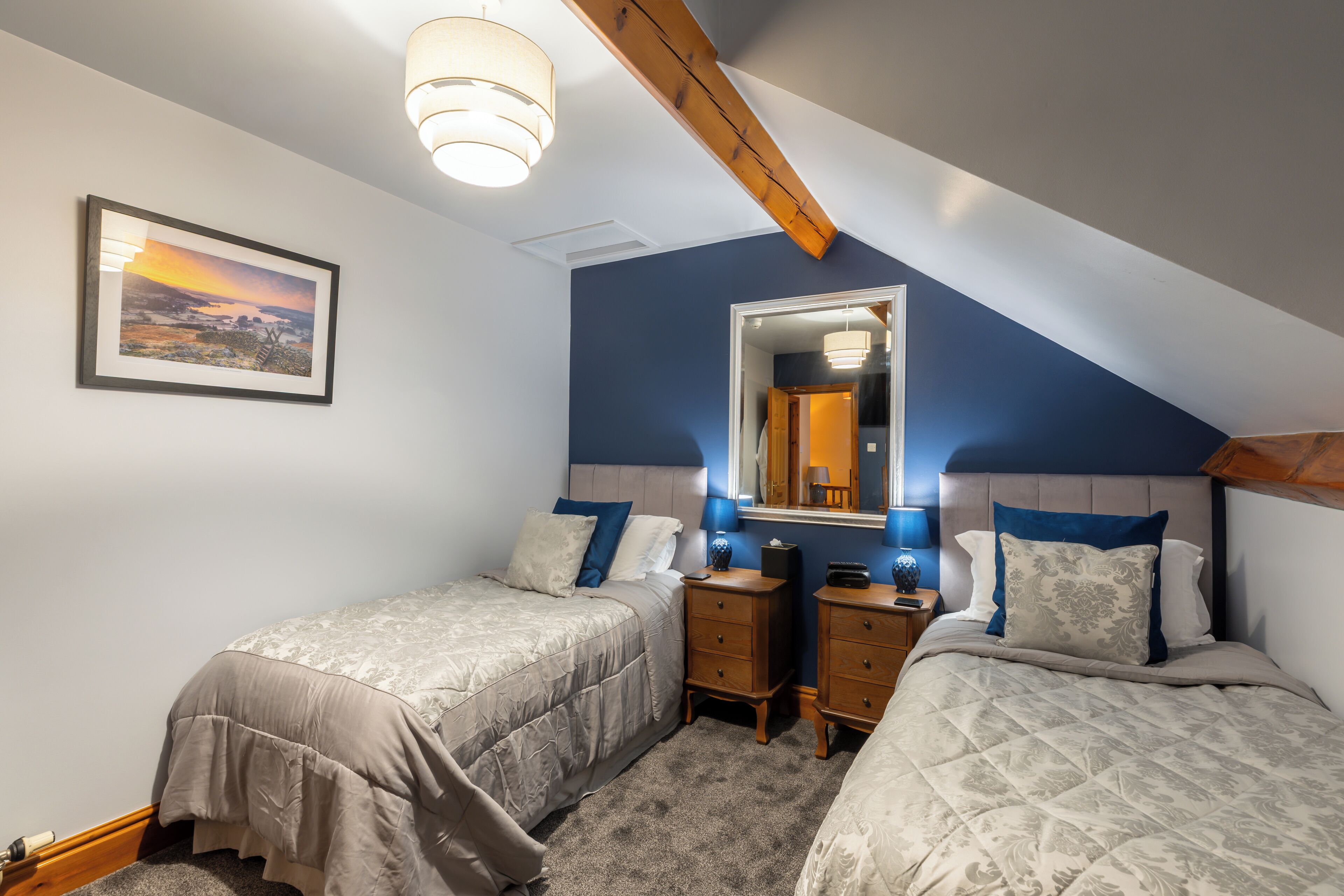 A bedroom with two beds, a dresser, a mirror, and a ceiling light.