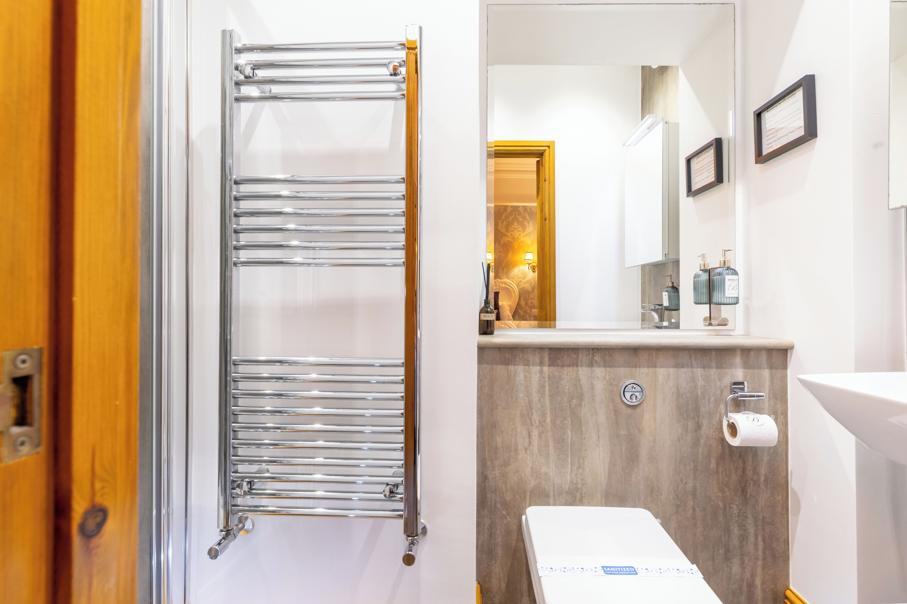 A bathroom with a towel rack, a toilet, a sink, and a mirror.