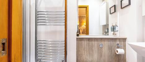A bathroom with a towel rack, a toilet, a sink, and a mirror.