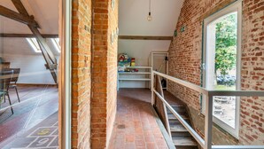 Un pasillo estrecho con paredes de ladrillo, una escalera y una ventana con vistas a zonas verdes.