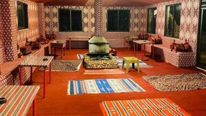 A cozy room with patterned walls, a central fireplace, and multiple seating areas. - Milky Way Nights Camp (Wadi Rum)