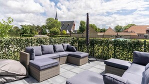 A patio with wicker furniture and a view of a church and residential buildings.