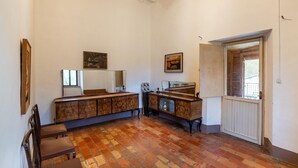 A room with a brick floor, wooden furniture, and a door leading to an outdoor area. - Belvilla by OYO Casa Ca Rio (Marche)