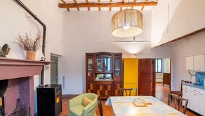 A dining area with a table set for two, a fireplace, and a wooden cabinet with glass doors. - Belvilla by OYO Casa Ca Rio (Marche)