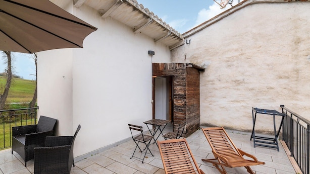 A patio with wicker chairs, a wooden table, and a wooden bench. - Belvilla by OYO Casa Ca Rio (Marche)