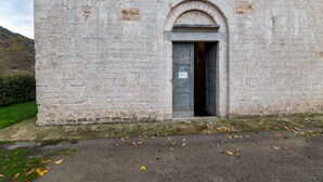 A stone building with a single arched doorway, a sign on the door, and a grassy area in front. - Belvilla by OYO Casa Ca Rio (Marche)
