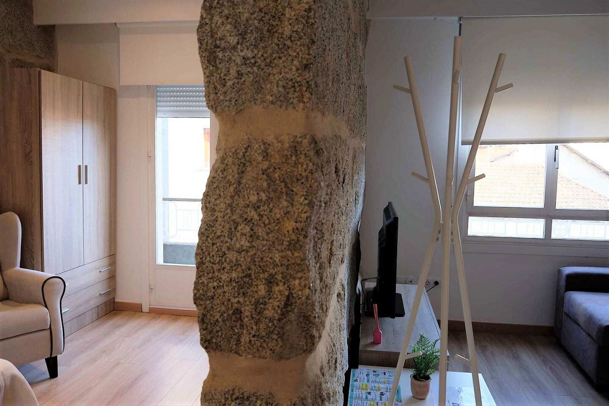 Una sala de estar con un gran pilar de piedra, muebles de madera y vistas a través de una ventana.