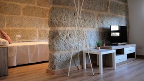 Ein modernes Wohnzimmer mit Steinwand, einem Bett, einem Fernseher und einem weißen Tisch.