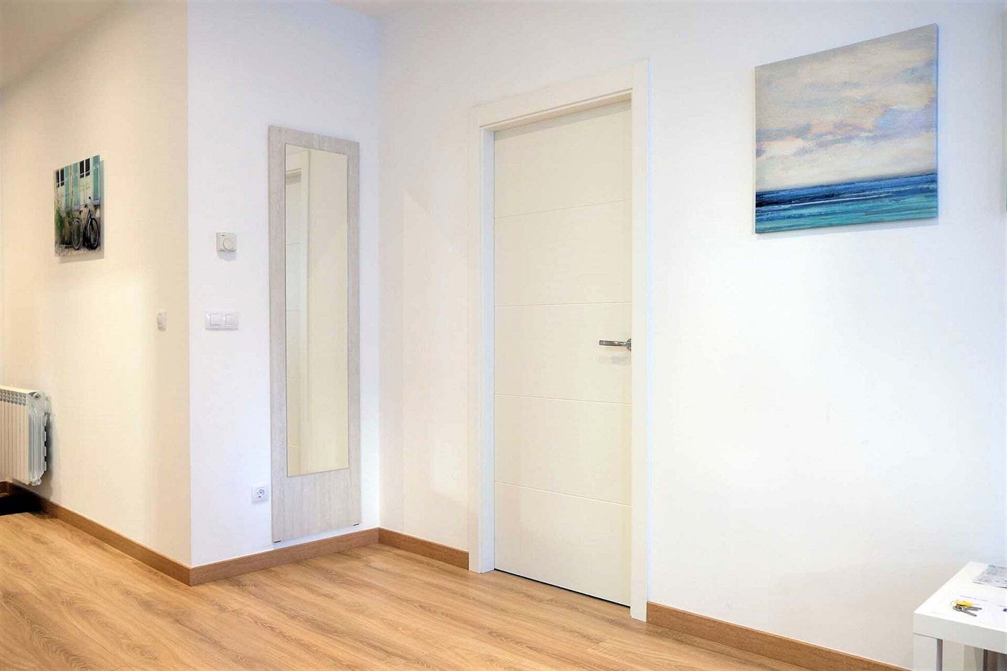 A hallway with a white door, a radiator, and a painting on the wall.