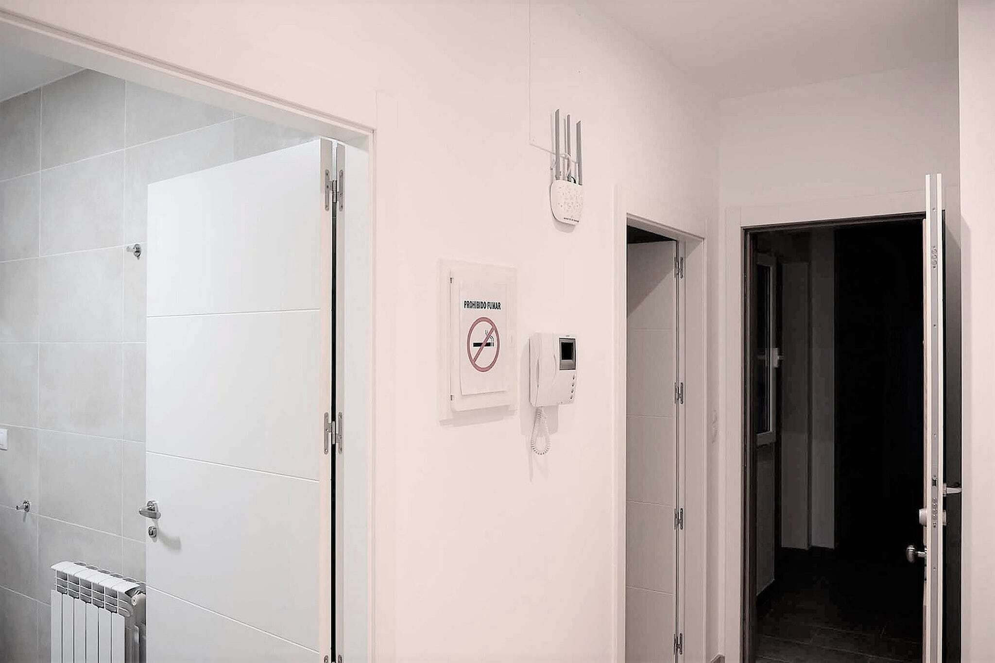 A hotel bathroom with a glass shower enclosure, a wall-mounted phone, and a sign indicating no smoking.