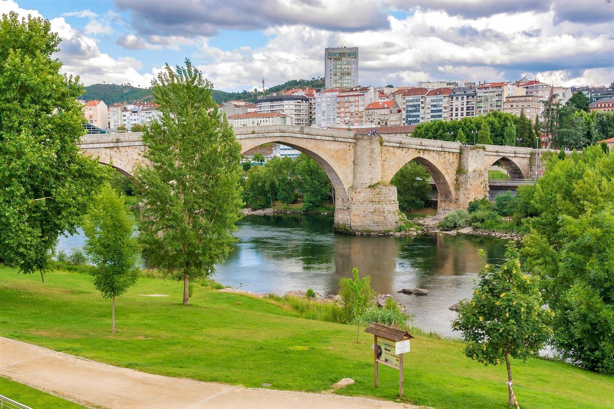 A stone bridge over a river with a cityscape in the background.