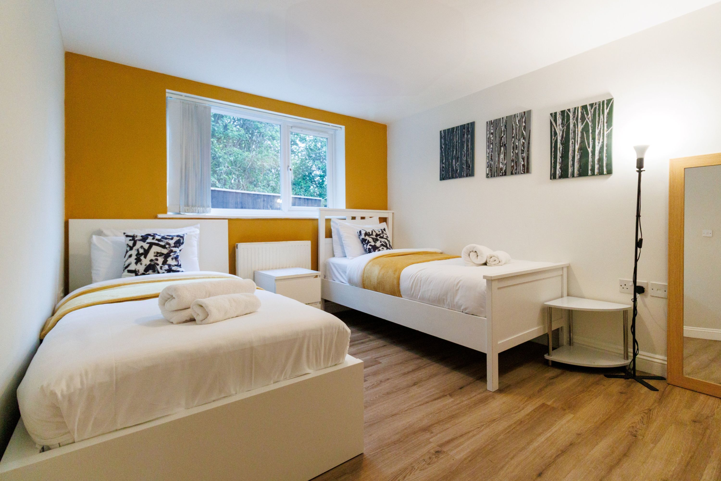 Une chambre d’hôtel avec deux lits, une fenêtre et des œuvres d’art au mur.