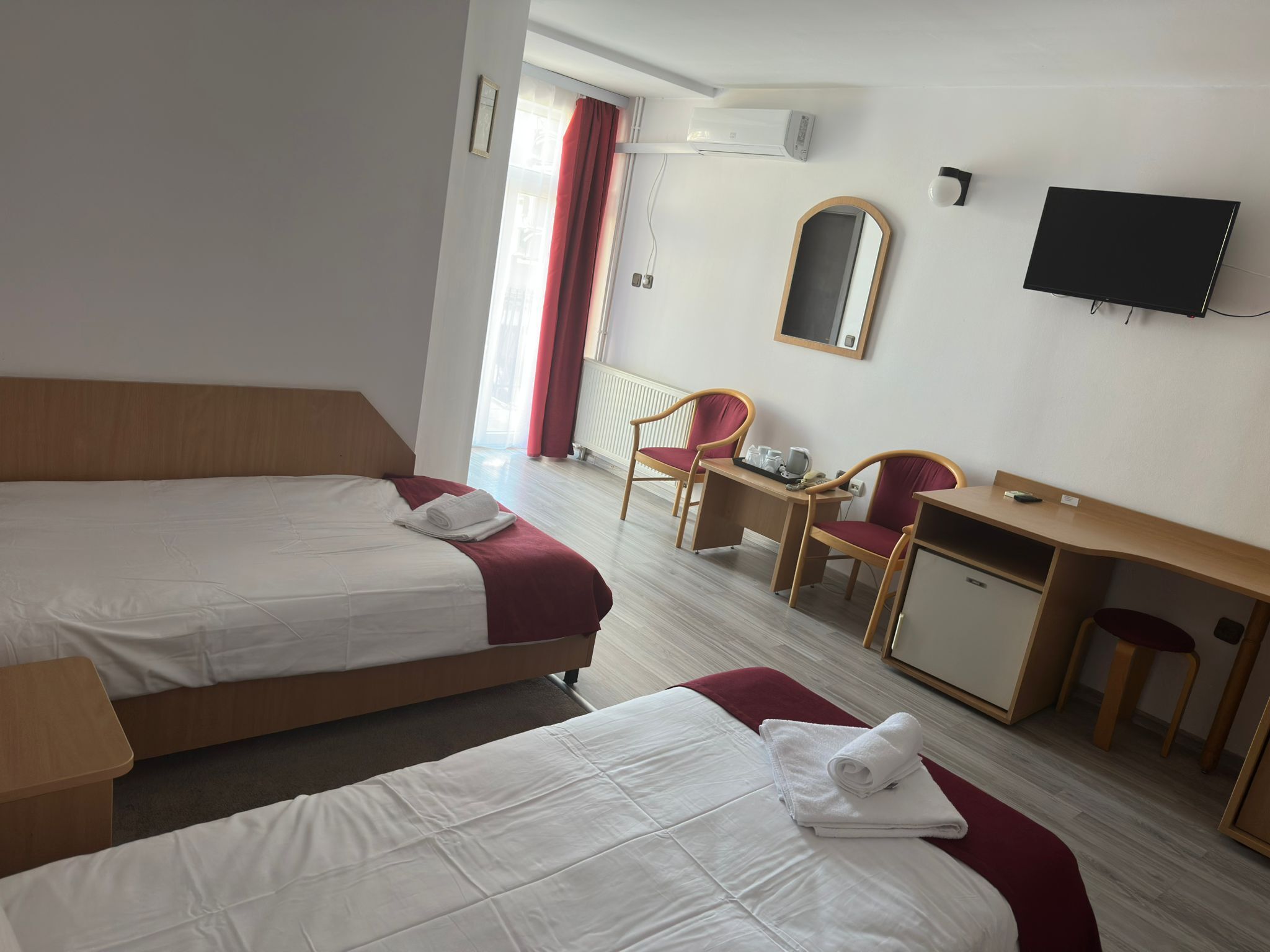 Una camera d'albergo con due letti, una scrivania, una sedia, una televisione e un condizionatore.