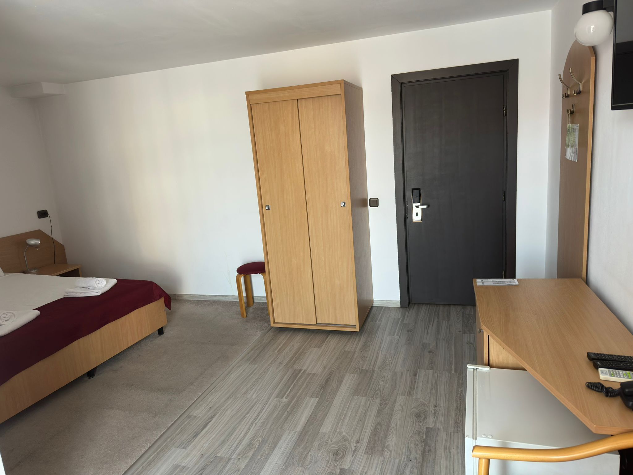 A room with a bed, a desk, a wardrobe, and a door.
