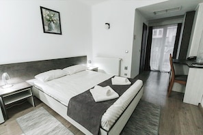 A hotel room with a bed, a desk, a chair, a radiator, and a picture on the wall. - Hotel Apollo Central (Sibiu)