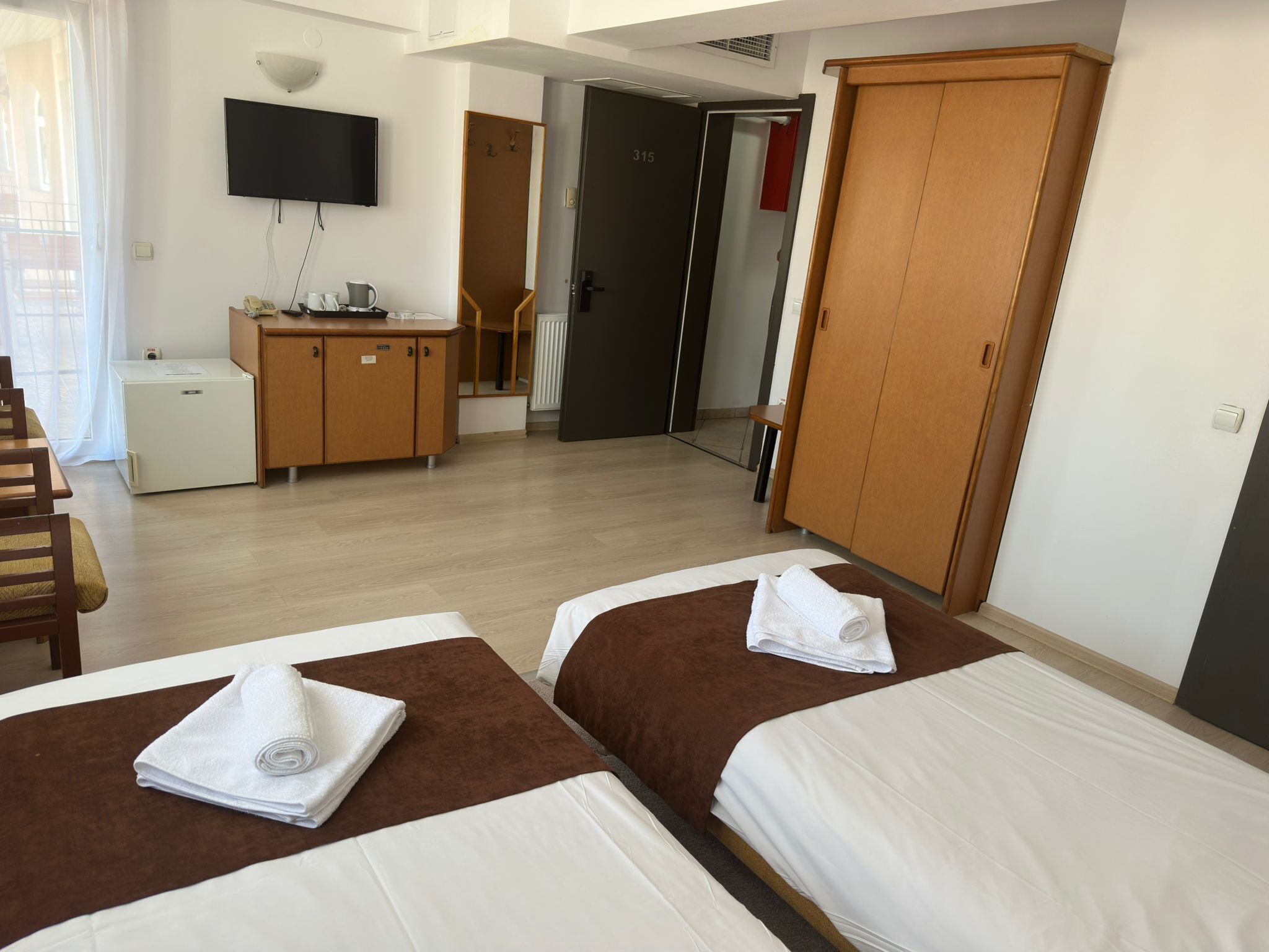 Una habitación de hotel con dos camas, un escritorio, un televisor y un armario.