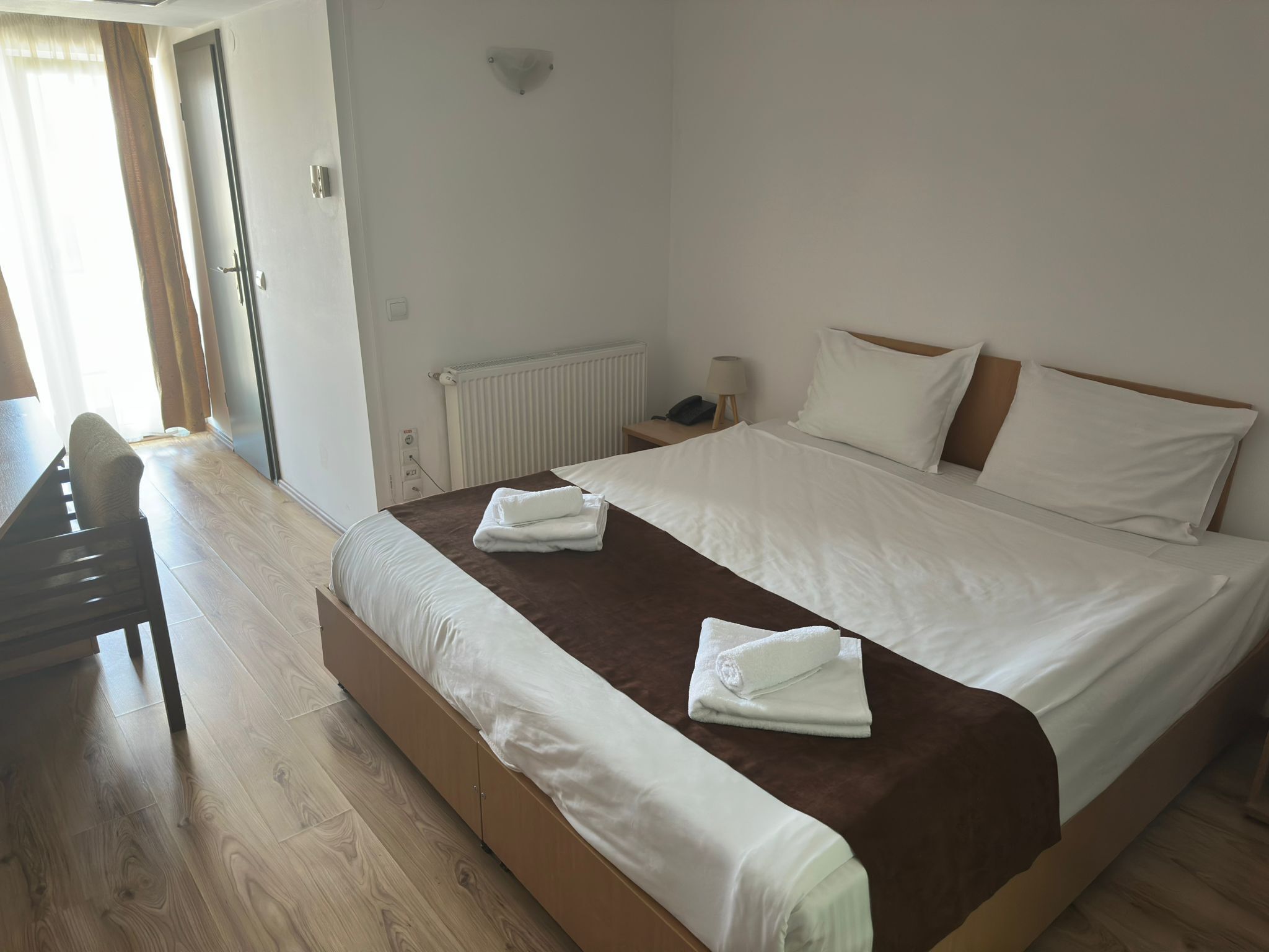 A hotel room with a large bed, a desk, and a chair.