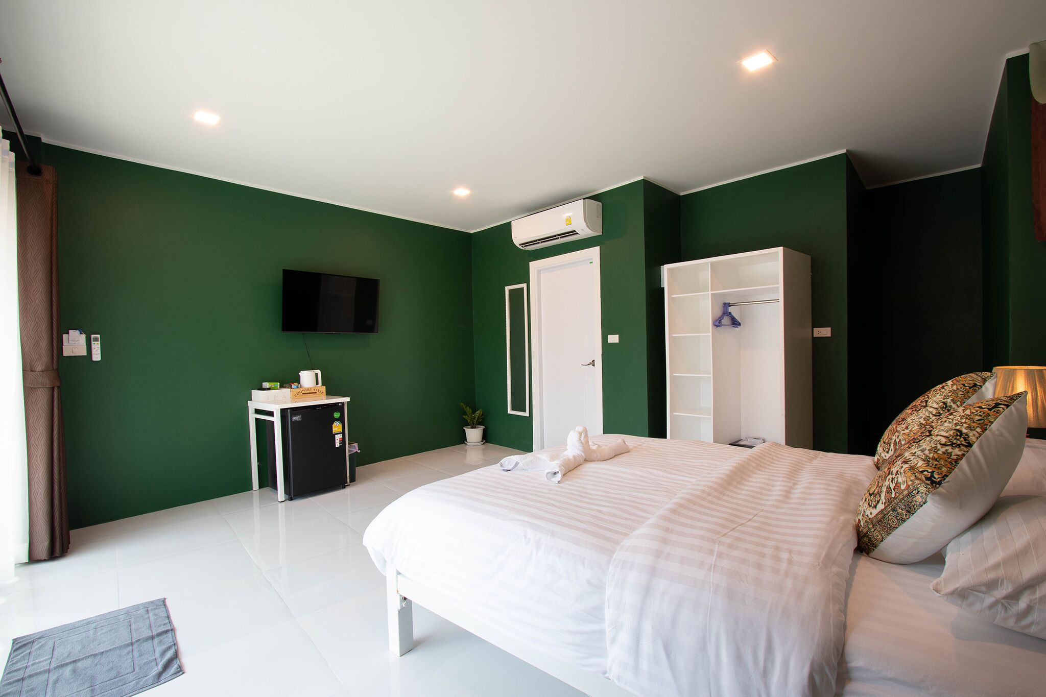 Un dormitorio con cama, armario, escritorio, aire acondicionado y televisión.