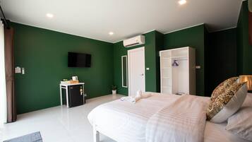 Un dormitorio con cama, armario, escritorio, aire acondicionado y televisión.