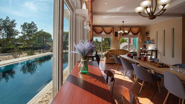 A spacious dining area with a view of a pool and outdoor scenery. - Hacienda Resort Mae Phim (Klaeng)