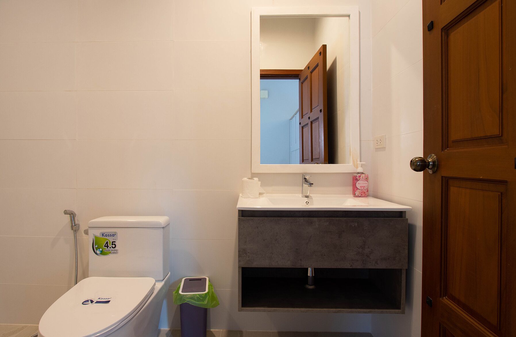 A bathroom with a toilet, a sink, and a mirror.