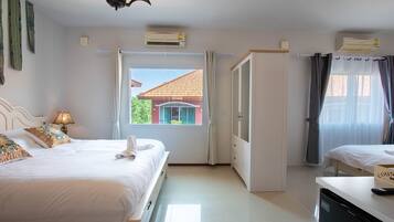 A hotel room with two beds, a wardrobe, a desk, and a window with a view of a building.