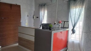 Una moderna recepción con decoración en gris y rojo, una puerta de madera y paredes con un diseño llamativo.