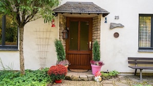 A house with a wooden door, number 25, a small porch, and potted plants. - Ferienhaus in Willingen nahe Skipisten (Willingen)
