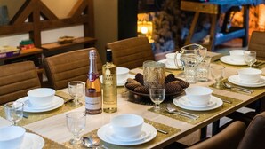 A dining table set with white plates, bowls, and cutlery, with bottles of wine and a pitcher. - Ferienhaus in Willingen nahe Skipisten (Willingen)