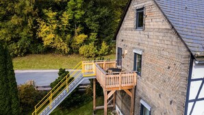 A two-story house with a wooden deck and a small outdoor seating area. - Ferienhaus in Willingen nahe Skipisten (Willingen)