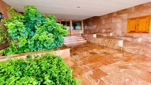 En rummelig lobby med marmorgulv, trappe og frodige grønne planter.