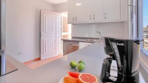 A modern kitchen with white cabinets, a coffee machine, and a view of the outdoors.