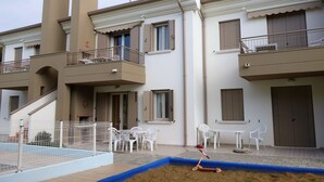 Un edificio residencial de dos pisos con balcones, piscina y zona de estar al aire libre.